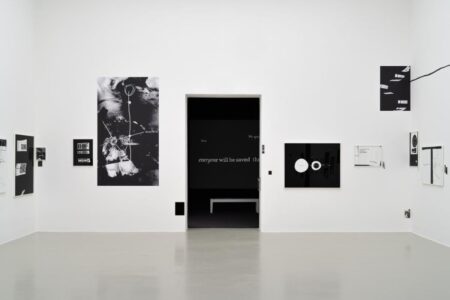 Minimalist art gallery with white walls displaying black and white abstract artworks. An open doorway in the center leads to a dark room with the phrase 