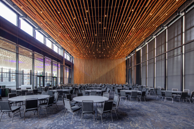 Meeting room with illuminated wood paneling. Circular tables with chairs.