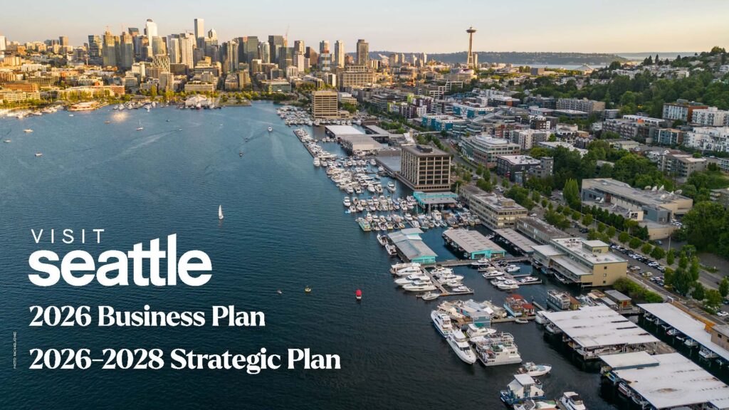 Aerial view of Seattle waterfront with marina, downtown skyline, and the Space Needle at sunset. Text reads: “Visit Seattle 2026 Business Plan, 2026-2028 Strategic Plan.”.