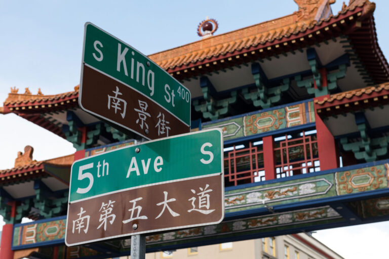 Street signs for S King St and 5th Ave S, adorned with Chinese translations, stand before a traditional Chinese gate with colorful architecture and intricate designs—a must-see landmark when exploring things to do in Seattle.