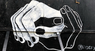 A mural of two hands grasping each other, one white, one black.