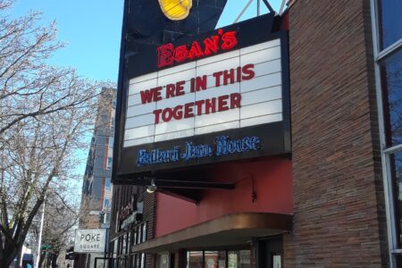 A brick building with a neon saxophone sign above a marquee that reads, 