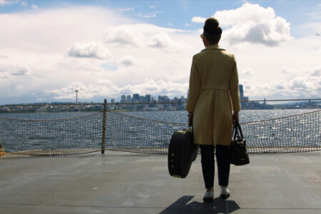 Emily King stands on a ferry looking wistfully at the city approaching.