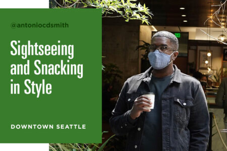 A person wearing a mask holds a drink while sightseeing in downtown Seattle. The image features the text: 