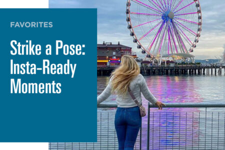 A person stands on a waterfront, facing a large Ferris wheel lit up with colorful lights. The reflection of the wheel shimmers on the water. A text box on the image reads: 