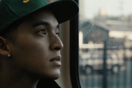 Still frame of a young man looking out the window of the light rail, a scene from Just a Kid From Seattle, a film by JJ Augustavo