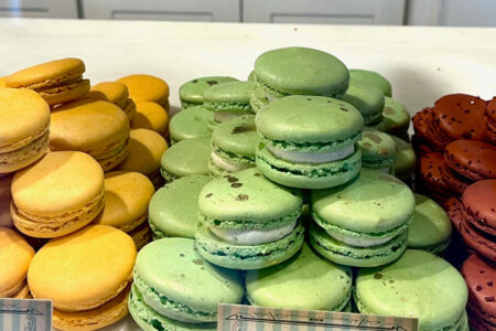 A photo of macrons in a display case. Yellow macrons are on the left, green are in the middle, and red are on the right.