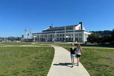 Two young girls walk down a path in South Lake Union Park toward MOHAI (Museum of History and Industry).