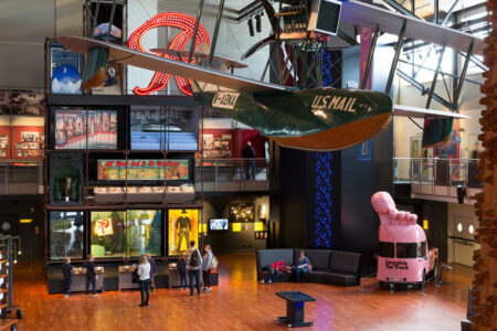 A wide angle view of MOHAI's lobby, showing key exhibits like the Rainier R, Lincolon's Toe Truck, and a Boeing seaplane mail runner.