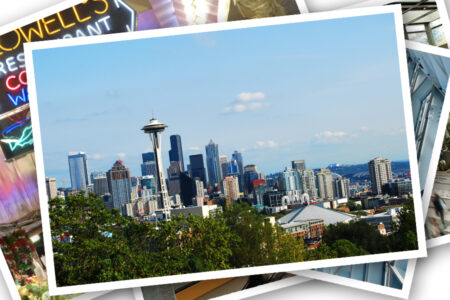 A panoramic view of Seattle's downtown skyline featuring the Space Needle and various skyscrapers under a clear blue sky. Greenery is visible in the foreground, adding contrast to the urban landscape.