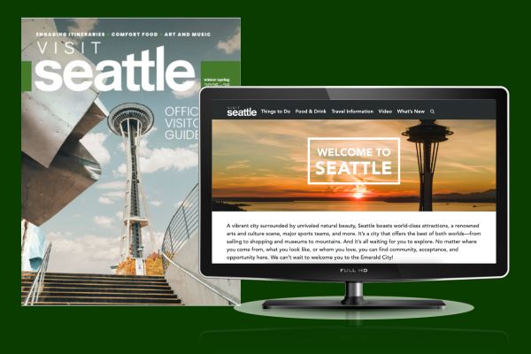 A printed Seattle visitor guide with the Space Needle on the cover stands next to a computer monitor displaying the "Welcome to Seattle" webpage, featuring a sunset view of the Space Needle.
