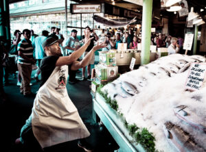 A fishmonger catching a fish thrown at Pike Place Fish Market.