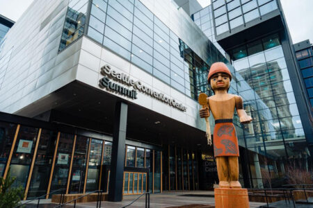 Seattle Convention Center. Steel and glass building with wooden sculpture of an Indigenous figure.