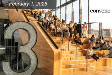 Large wooden steps in a modern building with many people sitting, reading, and using laptops.