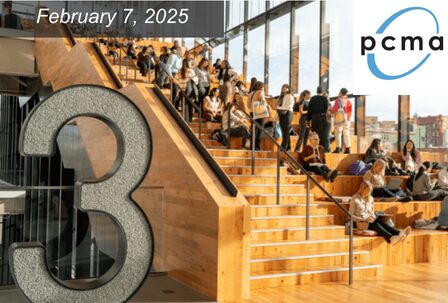 A large wooden staircase filled with seated people engaged in conversation and using laptops. A glass wall overlooks a cityscape.