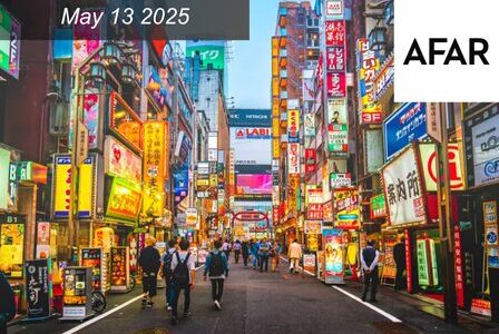 A busy street in Tokyo at dusk, filled with colorful neon signs and people walking.