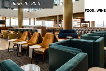 Modern lounge area with teal armchairs, yellow chairs, and small white tables. Large windows provide natural light.