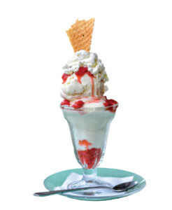 A photo of an ice cream sundae with red syrup drizzled over white ice cream and whipped cream. A light brown cookie is sticking out of the top.