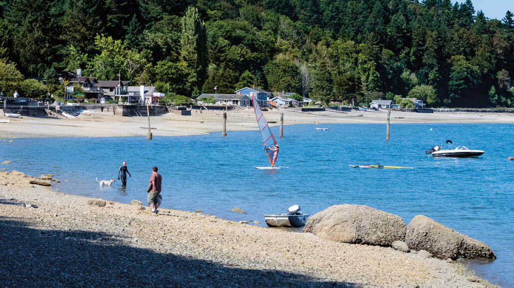 Multiple people and watercraft enjoying a stretch of beachfront