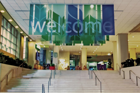 A wide staircase leads up to a lobby area with green and blue banners hanging from the ceiling, displaying the word 