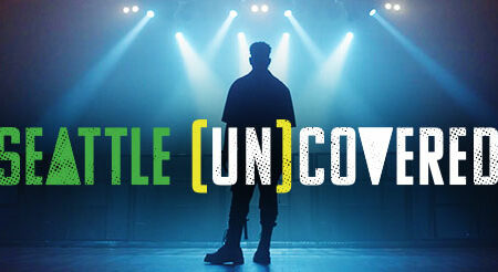 Silhouette of a person standing on stage under bright lights. The text 