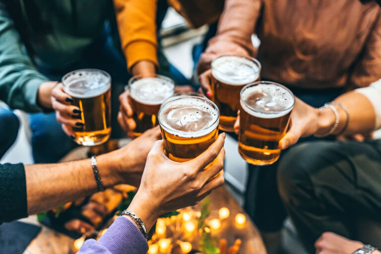 A group of people raise their glasses of beer in a toast, embodying the spirit of celebration and camaraderie. This scene, reminiscent of popular spots to explore for things to do in Seattle, features a blurred table and an inviting atmosphere perfect for forging connections.