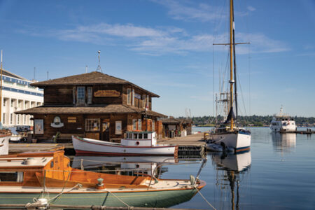 Four boats tied up to docks next to a wooden building on the water.