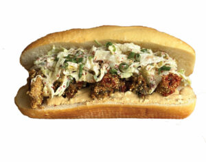 Sub sandwich with breaded fried foods, topped with coleslaw, in a sliced baguette on a white background.