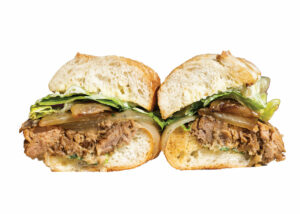 A sandwich cut in half showing shredded beef, grilled onions, and lettuce between two slices of crusty bread. The filling appears juicy and savory, with a generous amount of beef and fresh lettuce.
