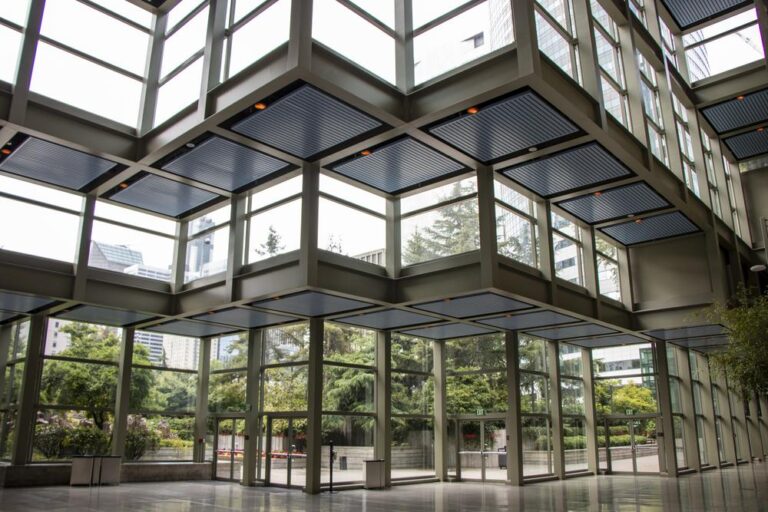Building lobby with glass doors and windows that look onto a green garden