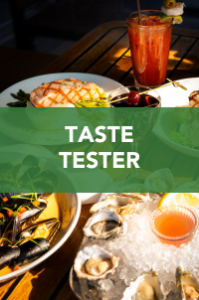 A table set with seafood dishes, including oysters, mussels, grilled fish, lemon wedges, and a reddish drink, with sunlight streaming in. Overlaid green banner reads "TASTE TESTER" in bold white text.