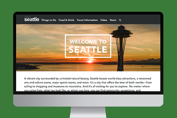 A computer screen displays a website titled "Visit Seattle" with a photo of the Space Needle at sunset. Text reads, "Welcome to Seattle." The website menu includes sections like Things to Do, Food & Drink, Travel Information, and Video.