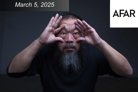 A person with a beard, wearing a black shirt, playfully holds their hands around their eyes.