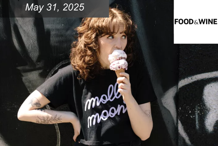 A woman with curly hair eats a large ice cream cone.